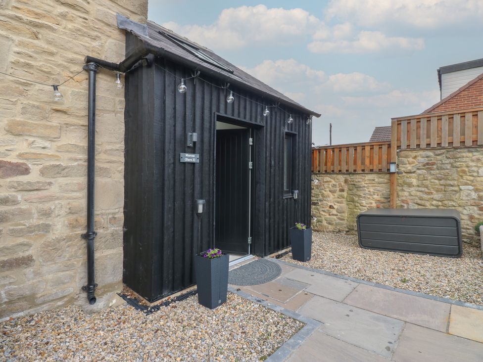 An entrance to a building with planters and gravel at Marcus Barn 3 in Ebchester
