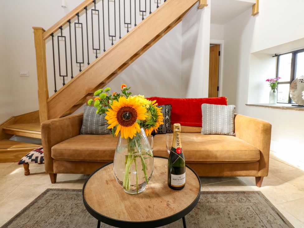 A living room with a sofa, flowers, and a staircase at Marcus Barn 3 in Ebchester