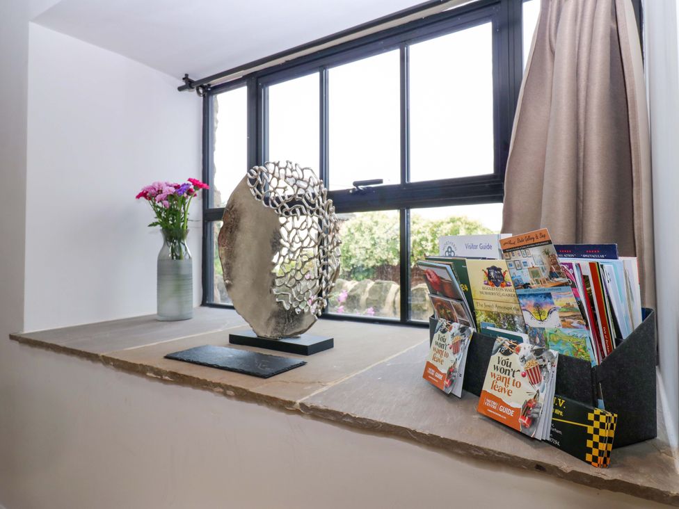 A window sill with a vase of flowers and brochures at Marcus Barn 3 in Ebchester