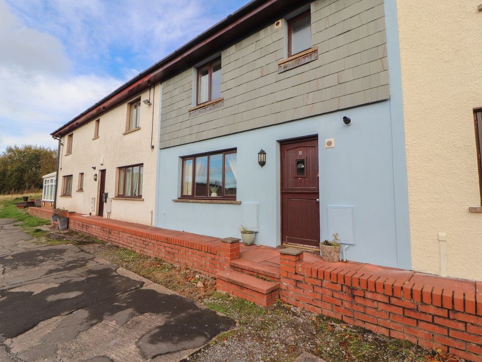 An exterior view of a house with a brick wall and windows at Valley View in Cleator Moor