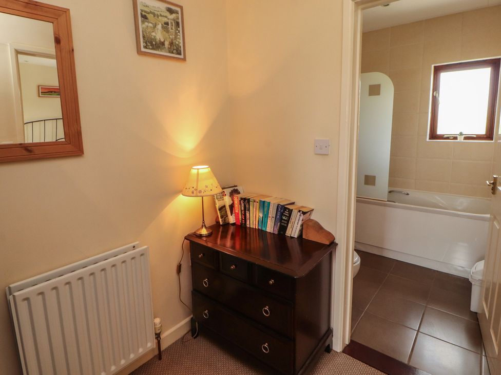 A bathroom with a bathtub and books on a shelf at Valley View in Cleator Moor