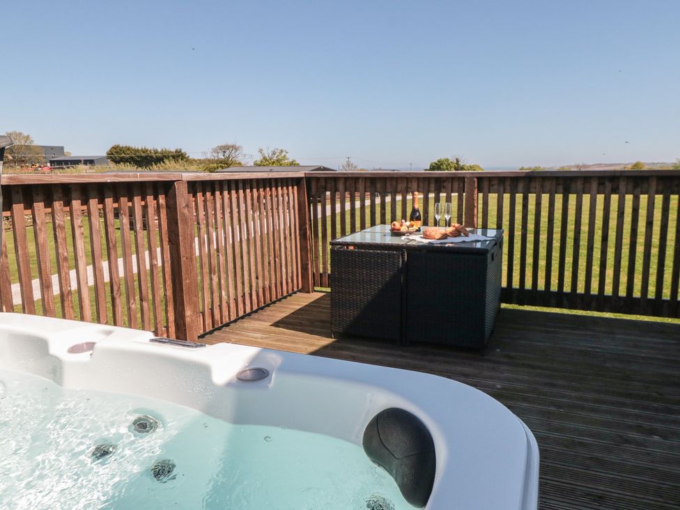 An outdoor area with a hot tub and a table set with food and drinks at Hazel Lodge in Whitby