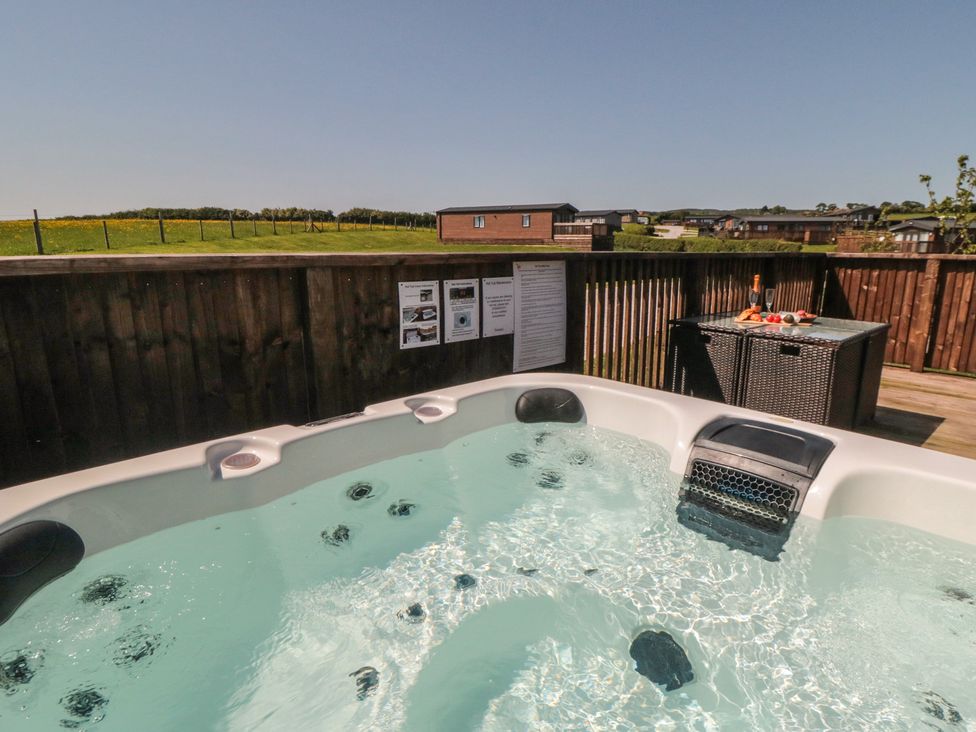 A hot tub with a table and champagne at Willow Lodge in Whitby