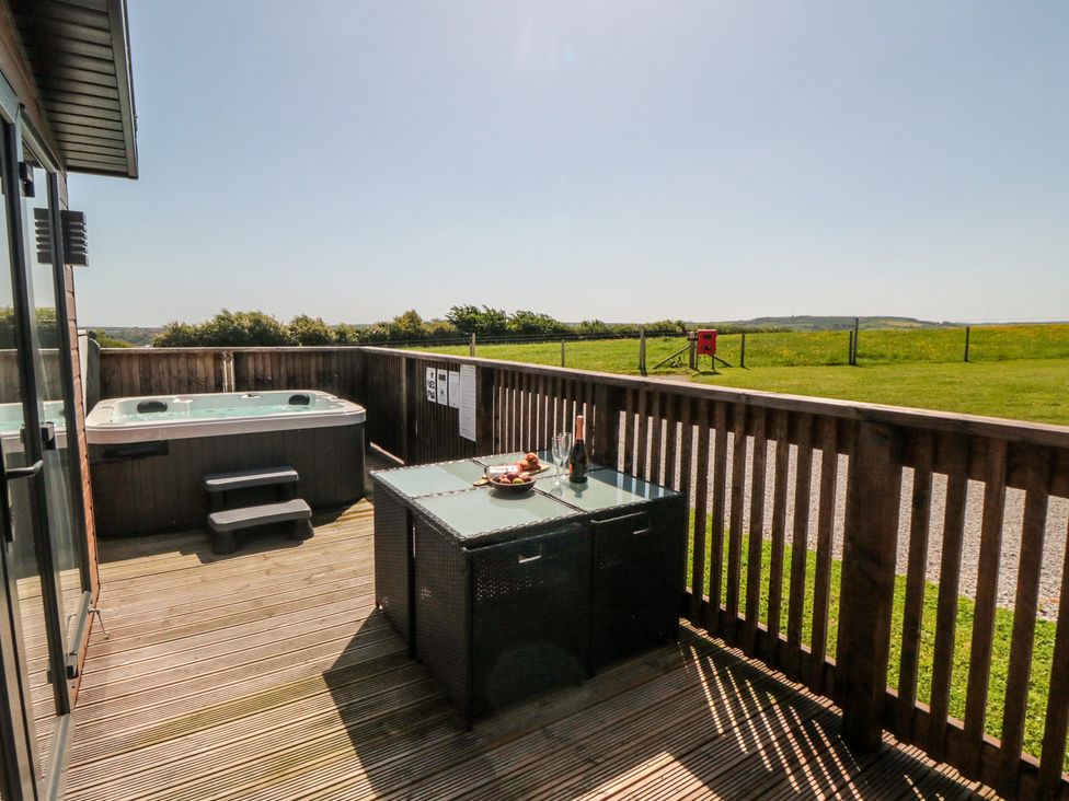 An outdoor seating area with a hot tub and table at Willow Lodge in Whitby