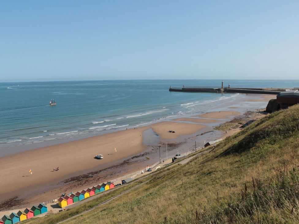A beach view with huts and a pier at Magnolia Lodge Whitby