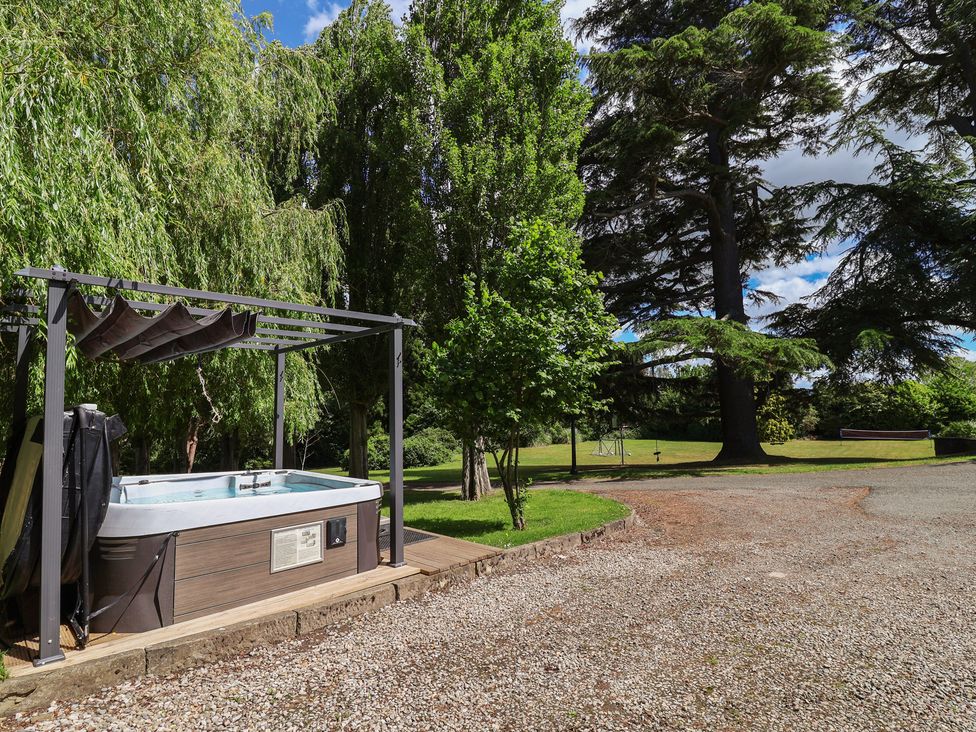 A hot tub under a canopy with trees in the background at The Colonnade in Trefnant