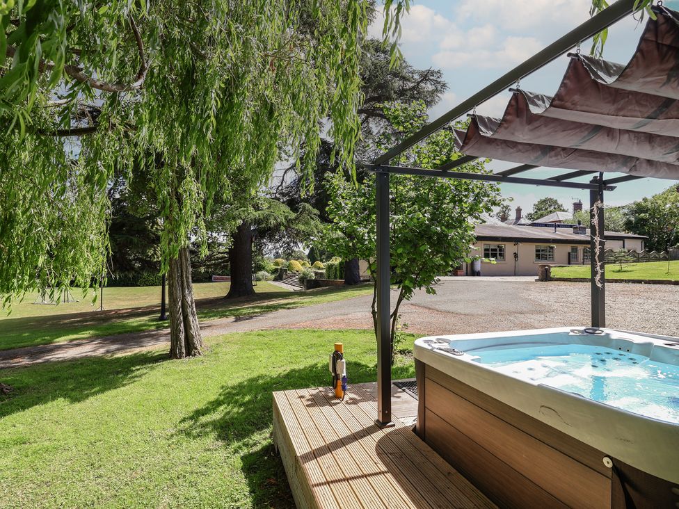 A hot tub on a deck with trees in the background at The Colonnade Trefnant