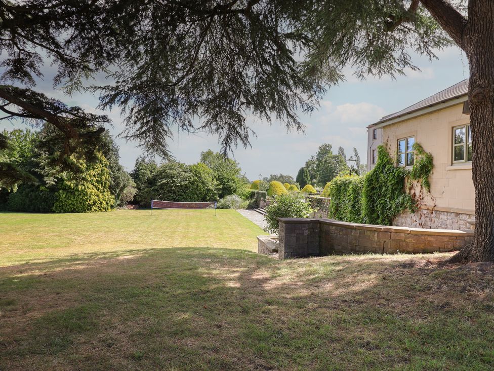 A garden with grass and a tennis net near a house at The Colonnade in Trefnant