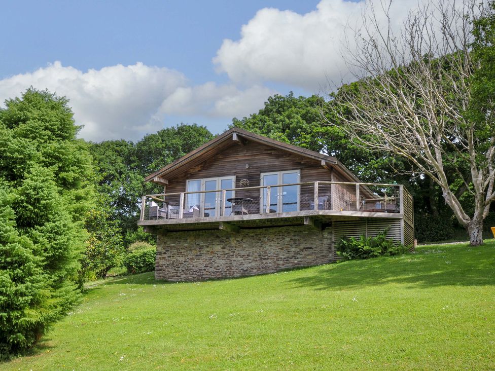 A wooden house with a deck surrounded by trees at 3 Lake View in Lanreath