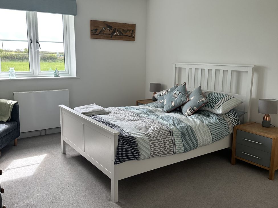 A bedroom with a bed and bedside tables at 9 Coastguard Cottages Woolacombe