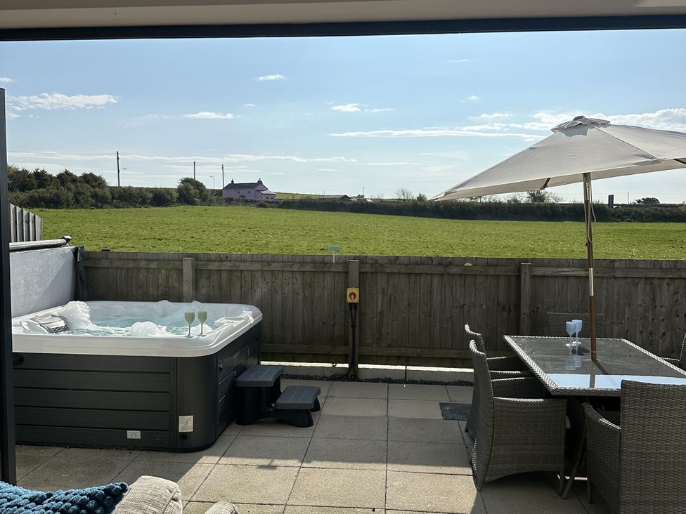 An outdoor area with a hot tub and table with chairs at 9 Coastguard Cottages Woolacombe