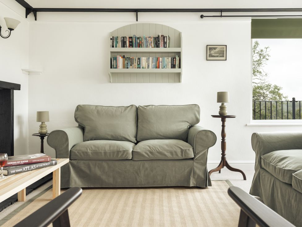 A living room with a sofa, lamp, and bookshelf at Tethers End in Lindeth near Bowness-On-Windermere