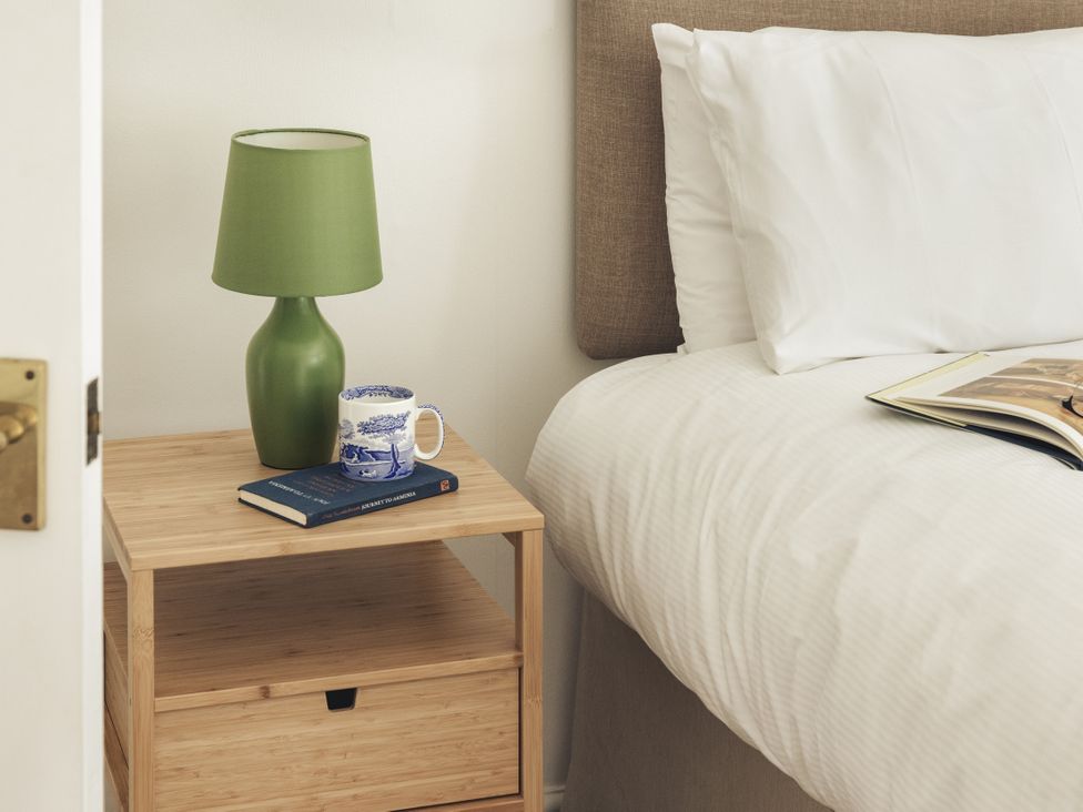 A bedroom with a lamp and a book on a nightstand at Tethers End in Lindeth near Bowness-On-Windermere
