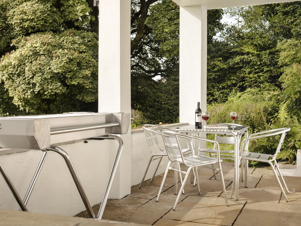 An outdoor seating area with a grill, table, and chairs at Tethers End in Lindeth near Bowness-On-Windermere