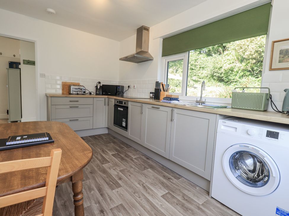 A kitchen with wooden table and washing machine at Tethers End Lindeth near Bowness-On-Windermere