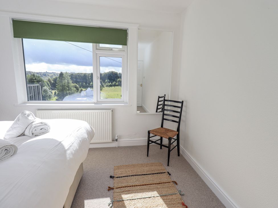 A bedroom with a bed and a chair at Tethers End in Lindeth near Bowness-On-Windermere