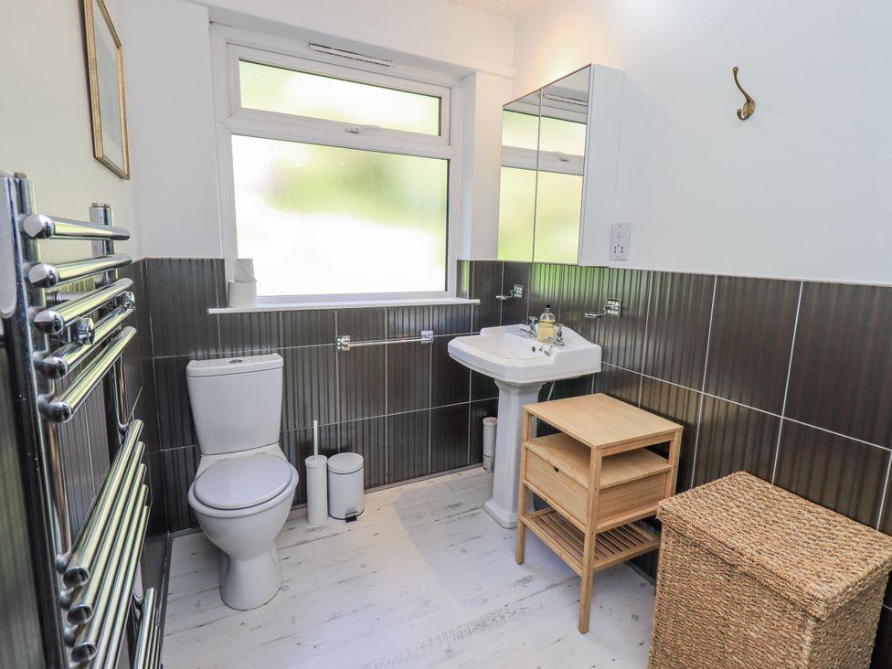 A bathroom with a toilet, sink, and storage furniture at Tethers End in Lindeth near Bowness-On-Windermere