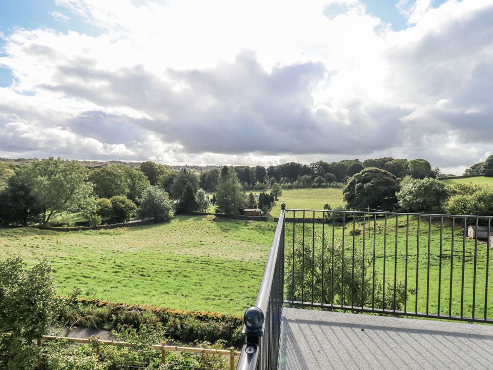 A view of a green field with trees and clouds at Tethers End in Lindeth near Bowness-On-Windermere
