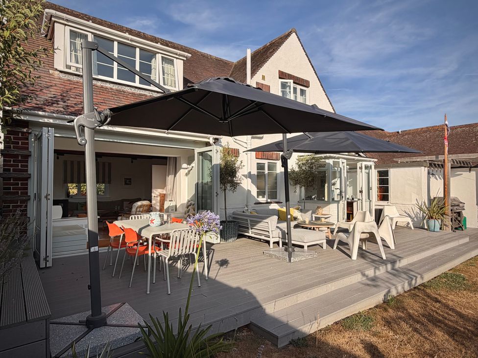 An outdoor area with dining furniture and umbrellas at Chantries in Bembridge