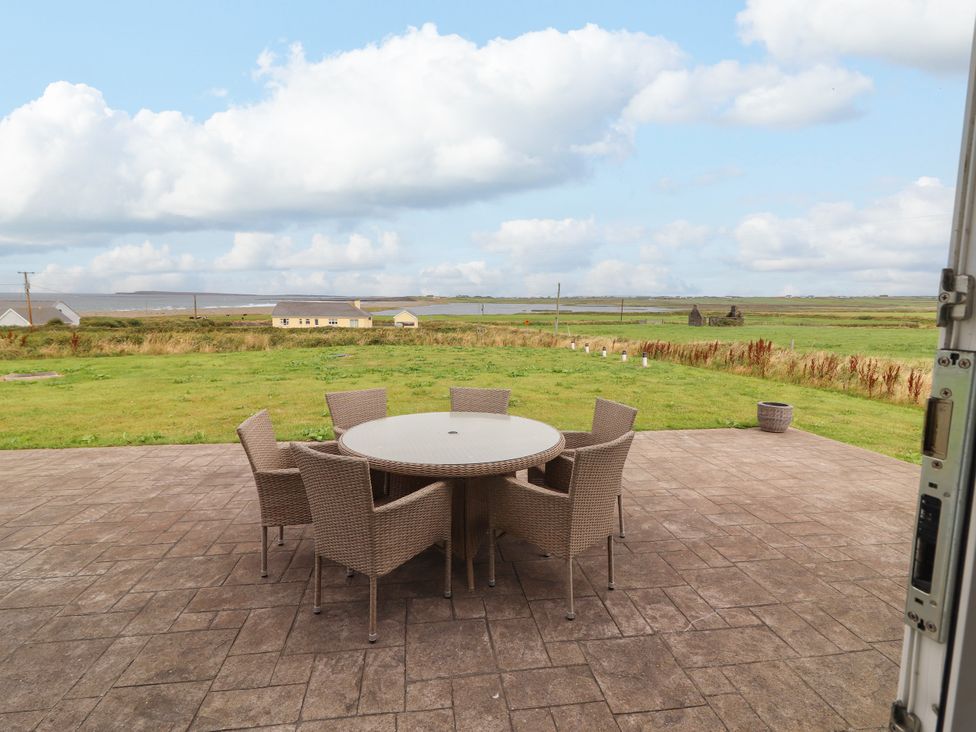 An outdoor area with a table and chairs overlooking grass at Carrowmore North in Doonbeg, County Clare