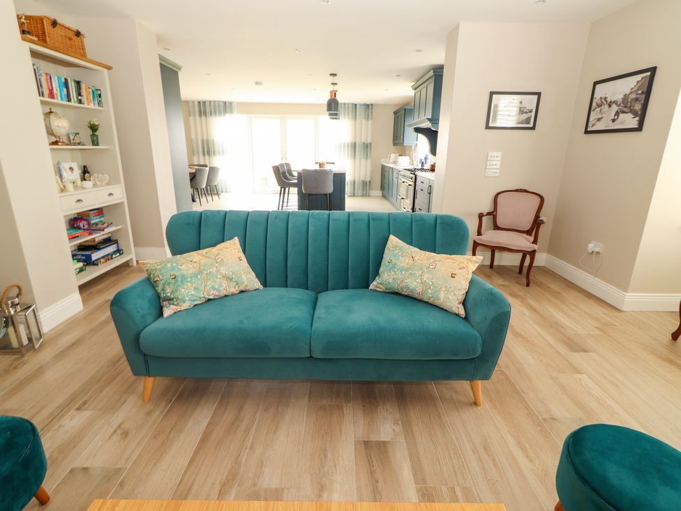 A living room with a teal sofa and bookshelf at Carrowmore North in Doonbeg, County Clare