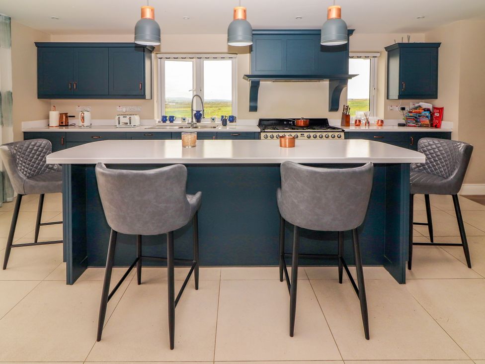 A kitchen with an island bar and stools at Carrowmore North in Doonbeg, County Clare