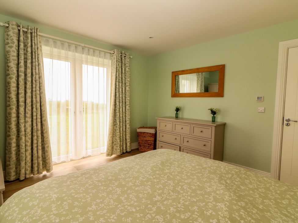 A bedroom with a window, dresser and mirror at Carrowmore North, Doonbeg, County Clare