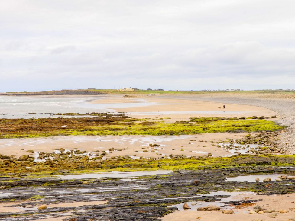 A beach with rocks and seaweed in the foreground at Carrowmore North in Doonbeg, County Clare