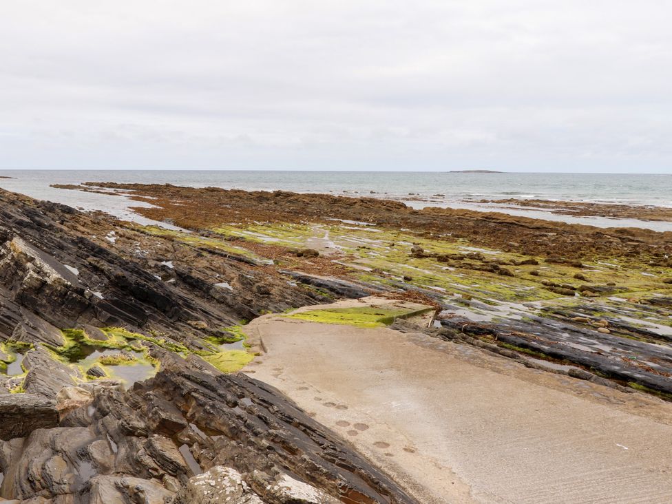 A rocky shoreline with seaweed and a concrete path at Carrowmore North in Doonbeg, County Clare