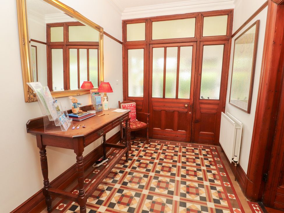 A hallway with a table, chair, and decorative features at Bracken Howe in Ambleside