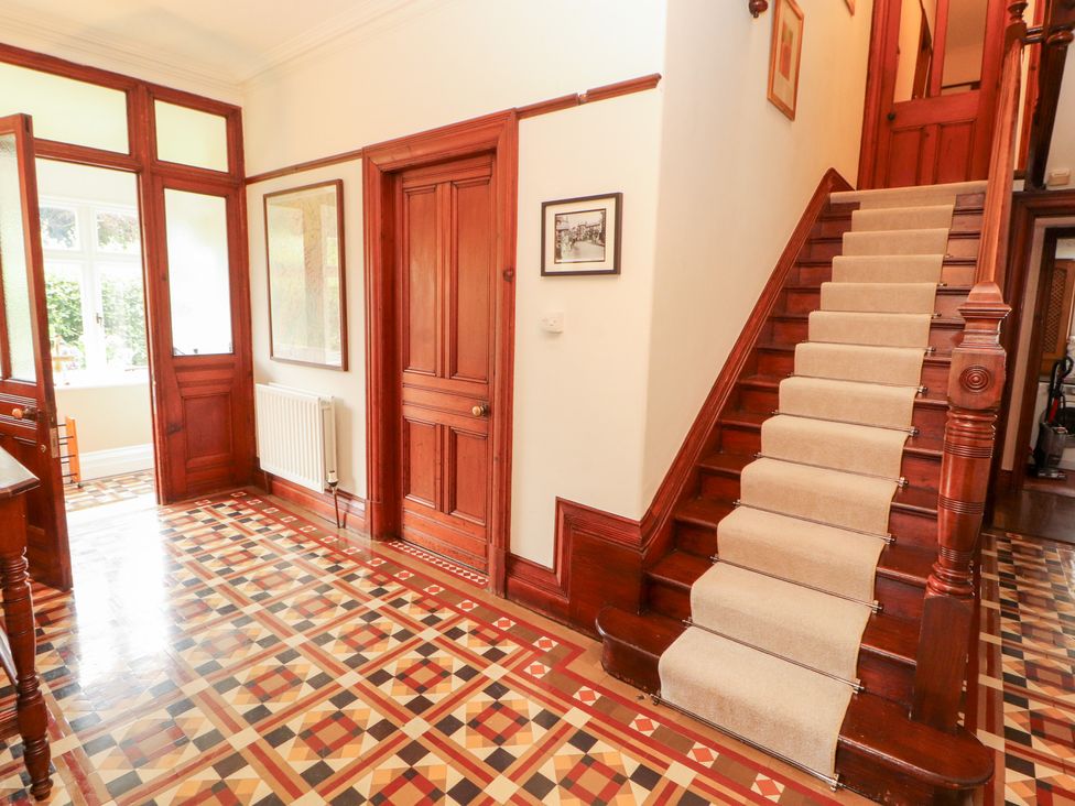 A hallway with a staircase and decorative floor tiles at Bracken Howe in Ambleside