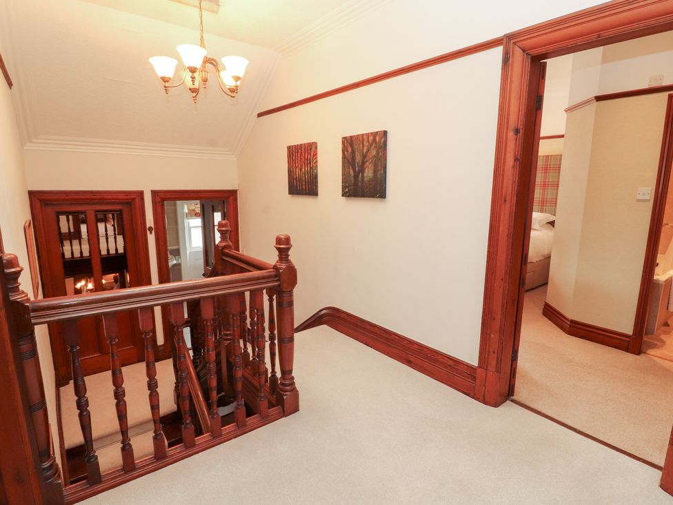 A hallway with a staircase and chandelier at Bracken Howe in Ambleside