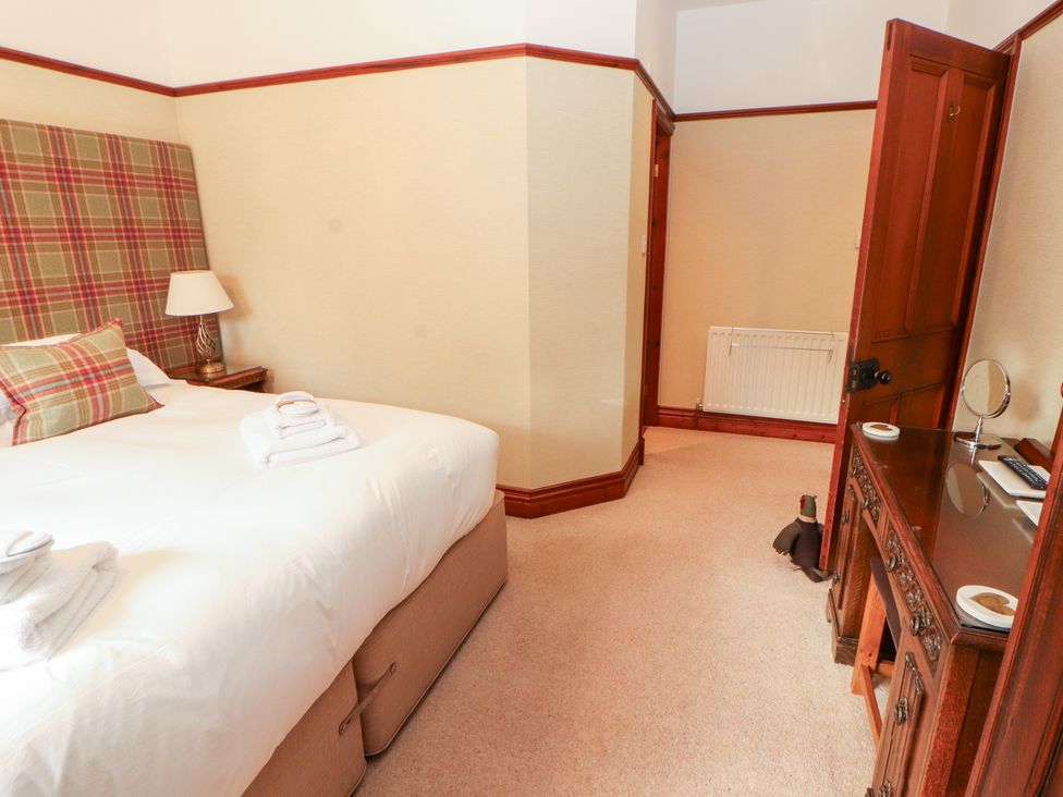 A bedroom with a bed and dressing table at Bracken Howe in Ambleside