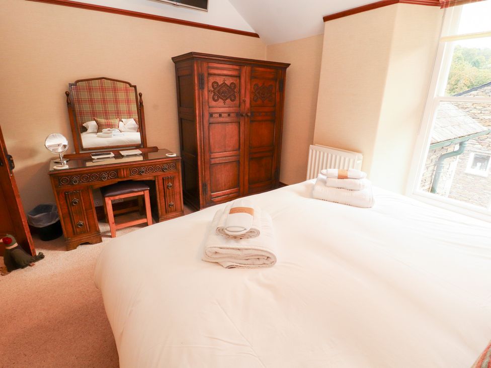 A bedroom with a bed, wardrobe, and dressing table at Bracken Howe in Ambleside