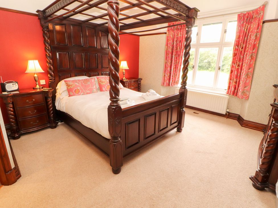 A bedroom with a four-poster bed and nightstand at Bracken Howe in Ambleside