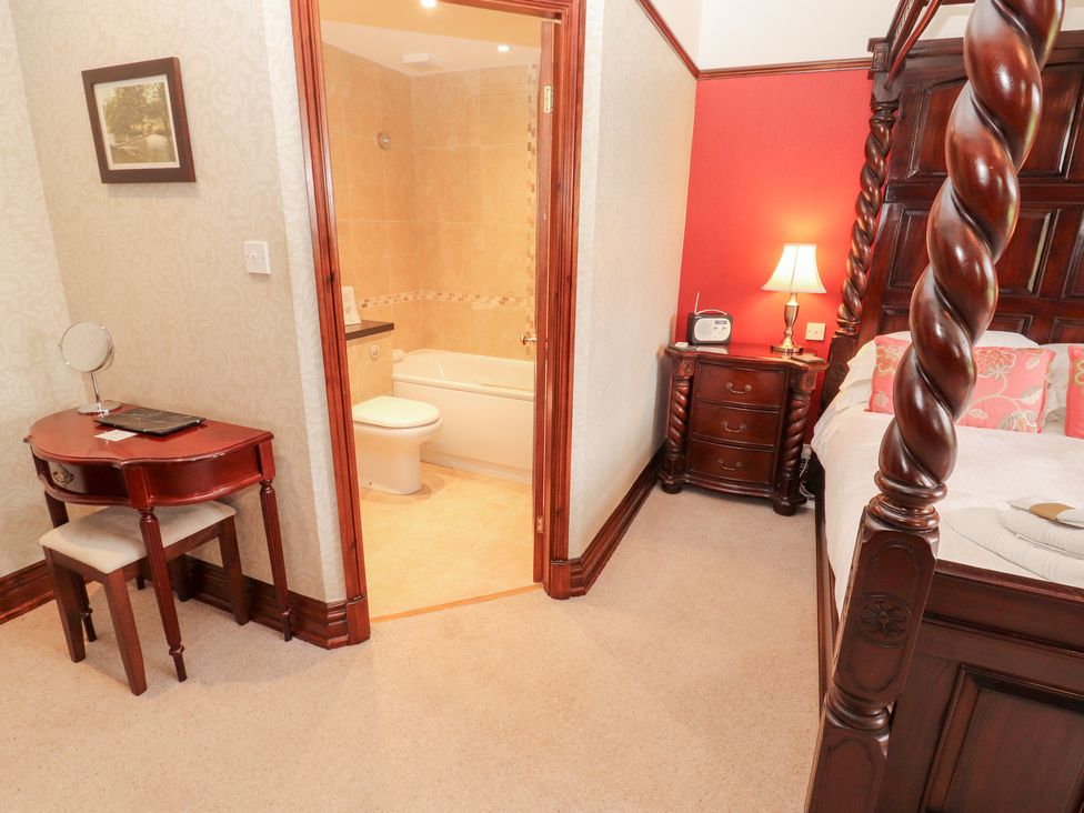 A bedroom with a bed and a bathroom entrance at Bracken Howe in Ambleside