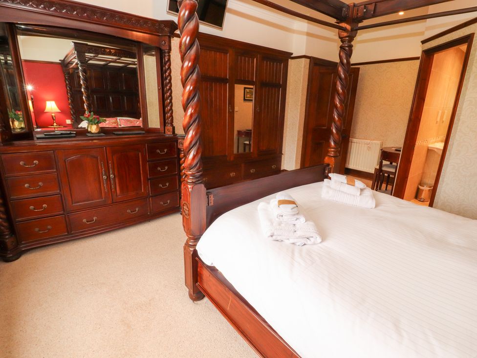 A bedroom with a four-poster bed and wooden furniture at Bracken Howe in Ambleside