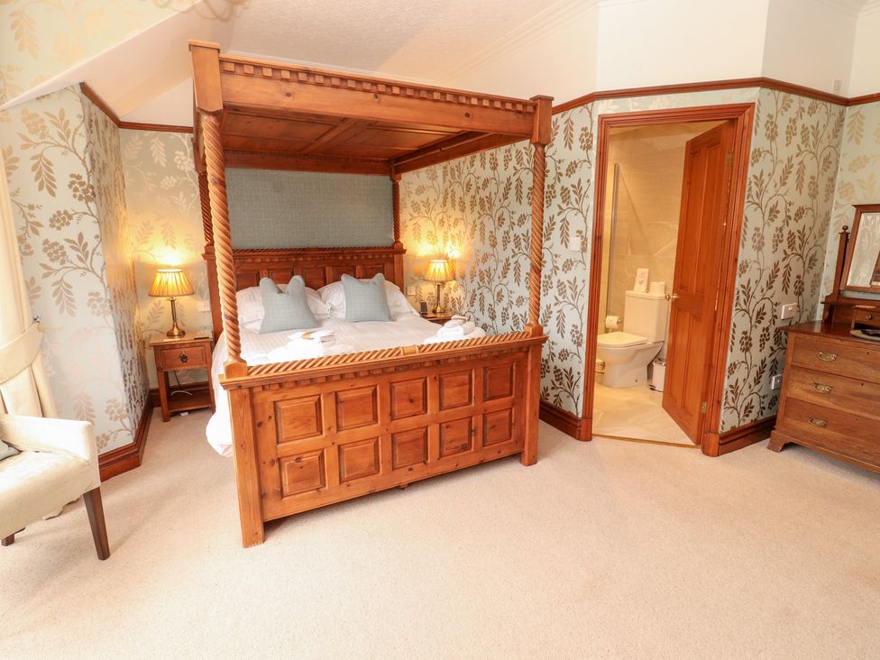 A bedroom with a four-poster bed and an attached bathroom at Bracken Howe in Ambleside