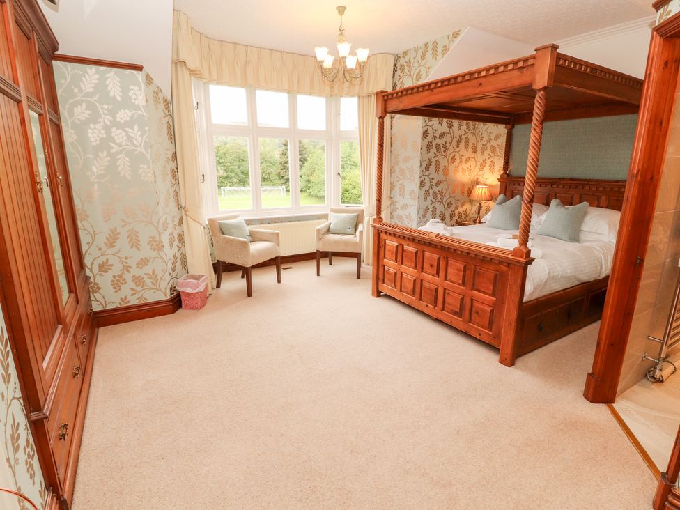 A bedroom with a four-poster bed and armchairs at Bracken Howe in Ambleside