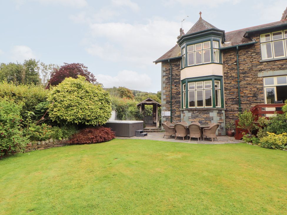 A garden with a house, hot tub and dining area at Bracken Howe in Ambleside