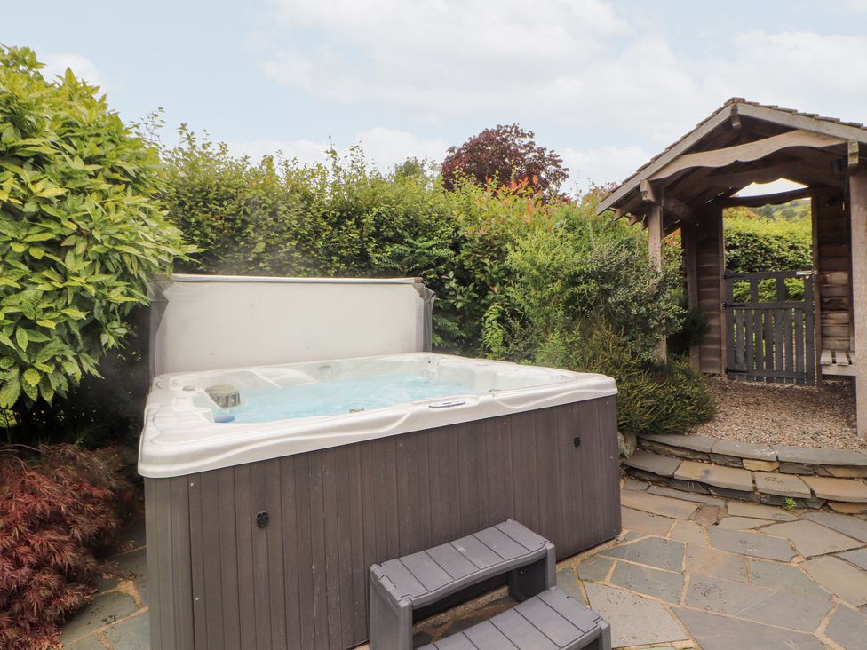 A hot tub with a wooden gazebo and plants at Bracken Howe in Ambleside