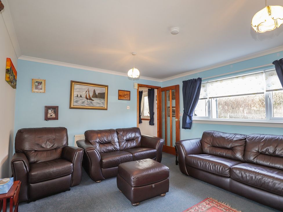 A living room with leather sofas and paintings at Arnaval in Carbost