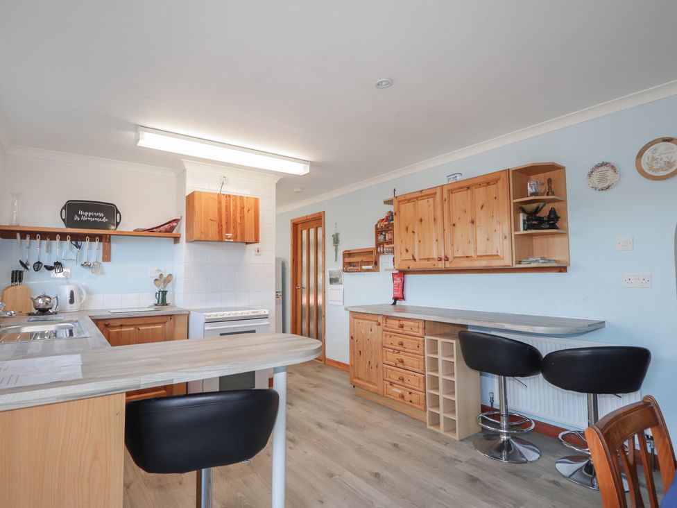 A kitchen with wooden cabinets and a table in Arnaval in Carbost