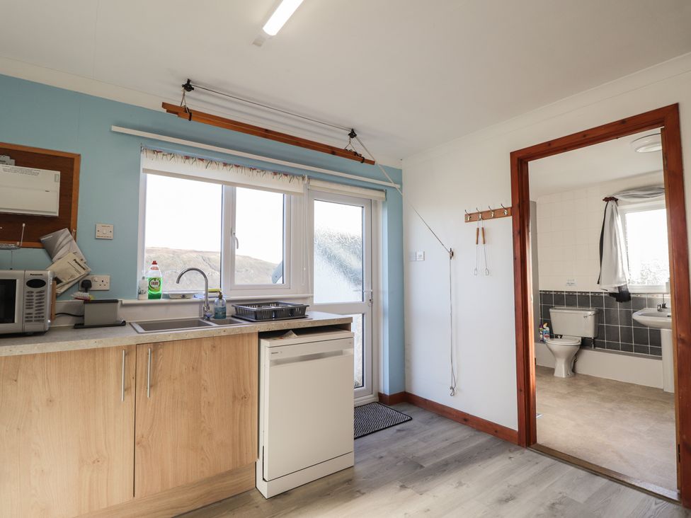 A kitchen with appliances and a doorway leading to a bathroom at Arnaval in Carbost