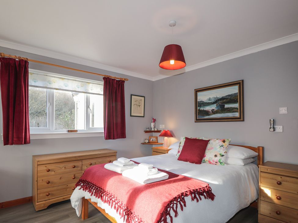 A bedroom with a bed and wooden furniture at Arnaval in Carbost