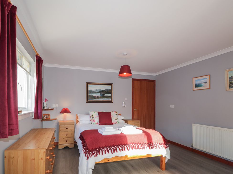 A bedroom with a bed, drawers, and a painting at Arnaval in Carbost