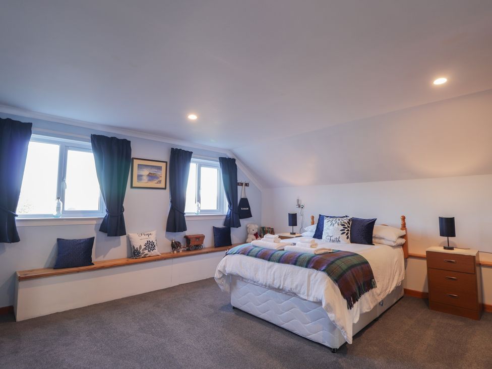 A bedroom with a bed and two windows at Arnaval in Carbost