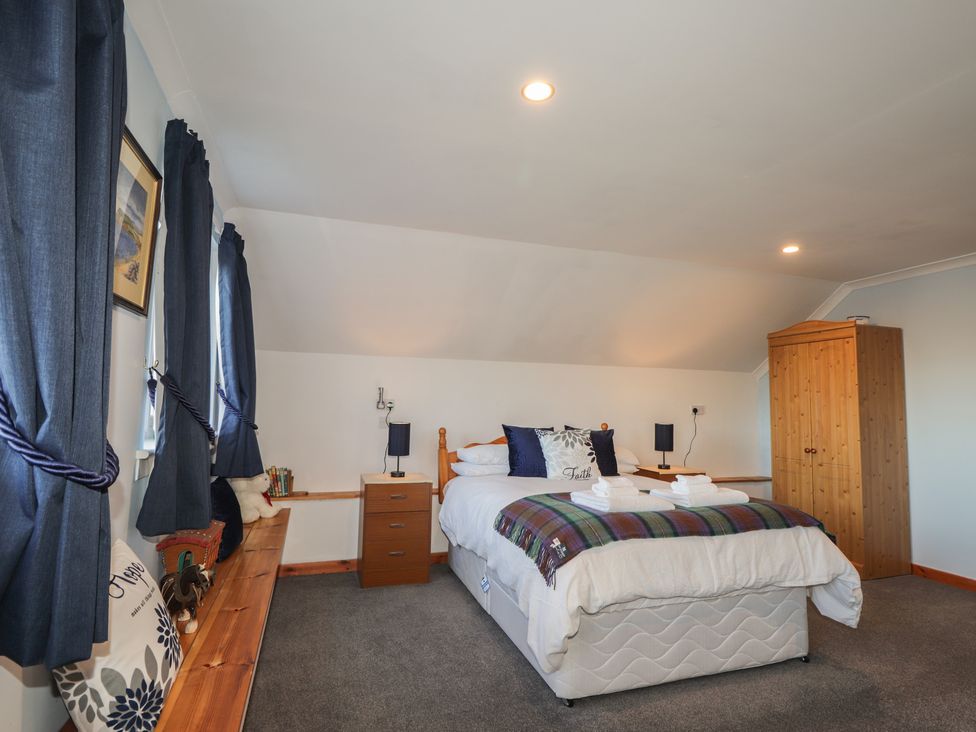 A bedroom with a bed, bedside lamps, and a wardrobe at Arnaval in Carbost