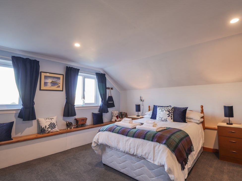 A bedroom with a bed, shelves, and windows at Arnaval in Carbost