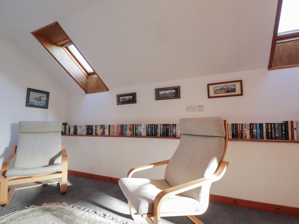 A reading room with armchairs and bookshelves at Arnaval in Carbost
